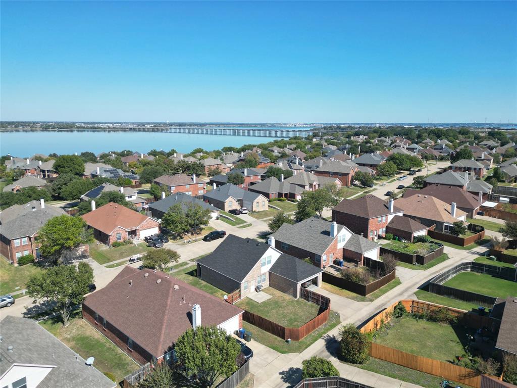 Neighborhood aerial panorama showing surrounding homes and streets, with a large body of water visible beyond the rooftops.