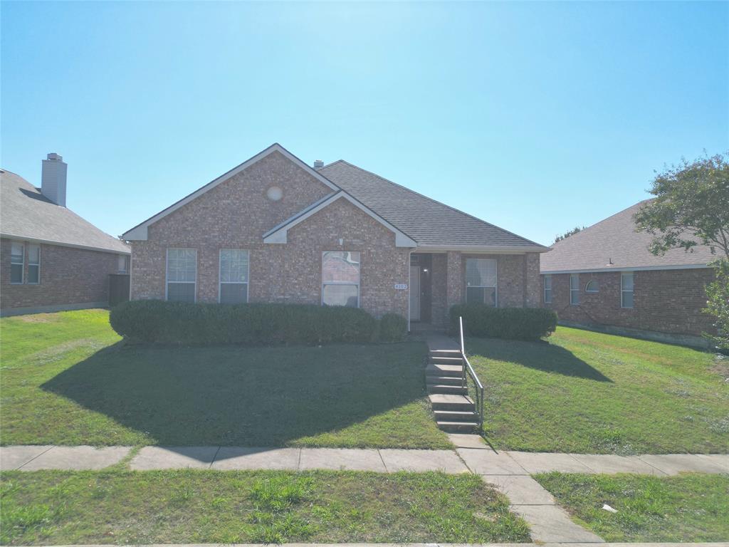 Straight-on front exterior view showing the brick facade, roofline, front lawn, and walkway to the entrance.