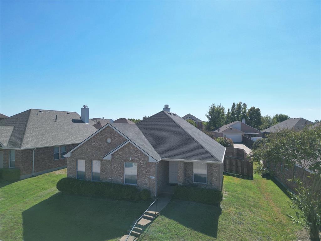 Elevated front view highlighting the roofline, chimney, front exterior, and the walkway approaching the entry.