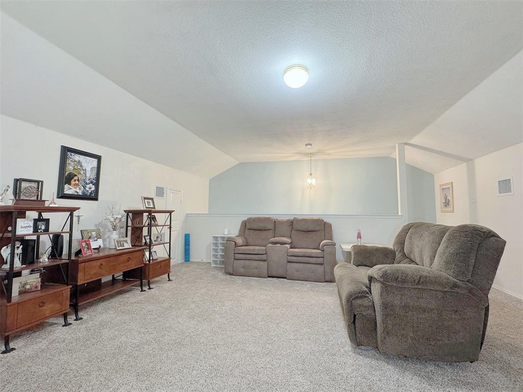 Reverse view of the furnished living room, showing the ceiling profile, seating area, and adjoining interior openings.