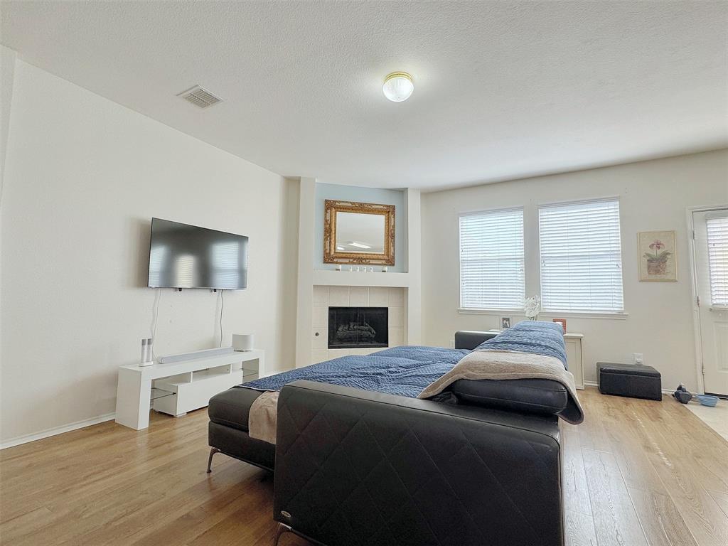 Alternate view of the fireplace living area, showing the seating arrangement, windows, and the connection to the kitchen.