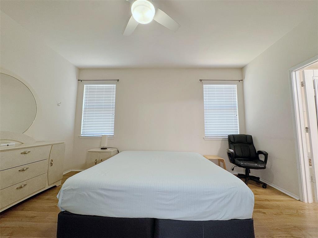 Bedroom with wood-look flooring, two windows, a ceiling light, and space for a bed and additional furnishings.