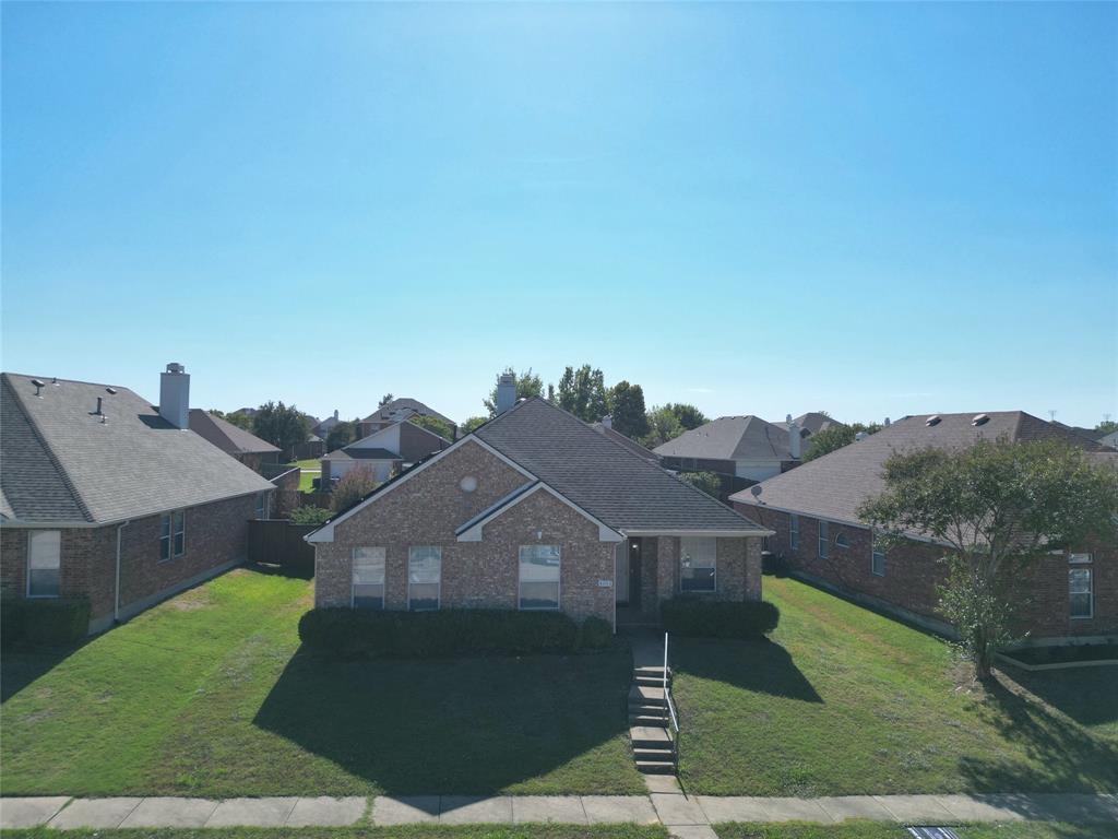 Additional elevated front view showing the house, lawn, roofline, and its position beside neighboring homes.