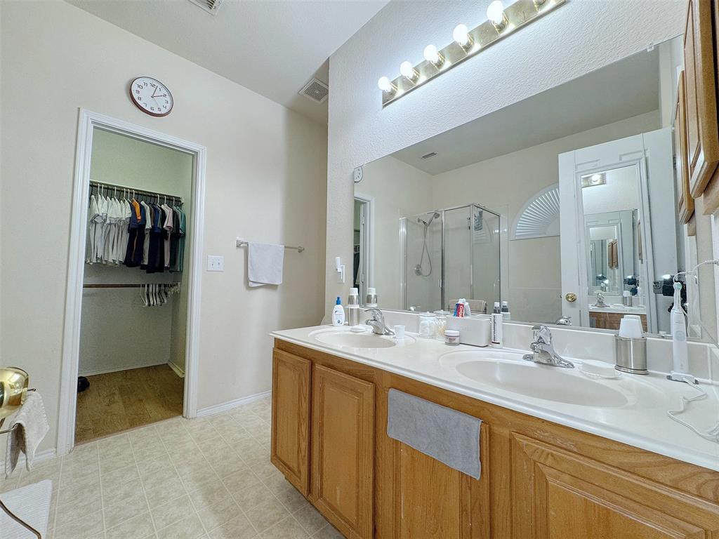 Alternate bathroom view highlighting the long wood vanity, mirror, overhead lighting, and countertop with sinks.