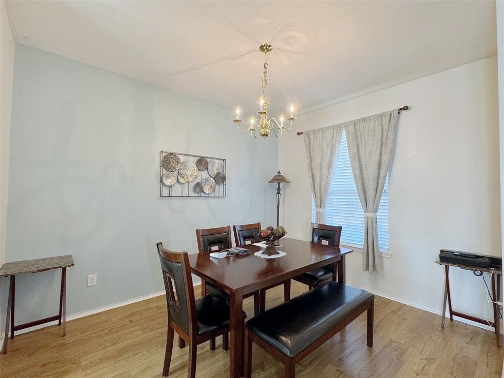 Dining area with a chandelier, window treatments, wood-look flooring, and space for a dining table and additional furnishings.