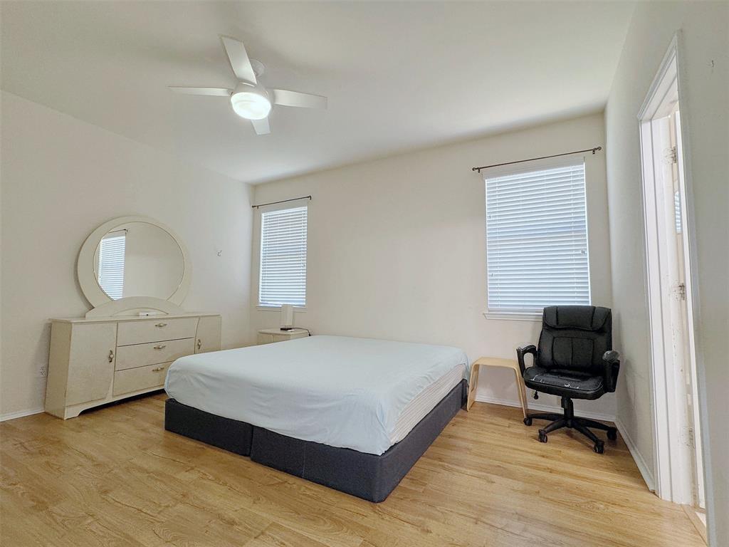 Alternate angle of the same bedroom, showing the window placement, wood-look flooring, and arrangement of the bed and furnishings.