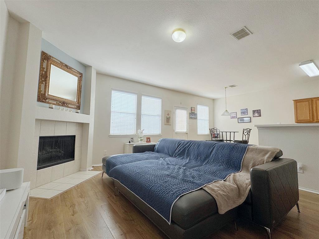 Fireplace-side living area with a white mantel, multiple windows, wood-look flooring, and room for seating around the hearth.