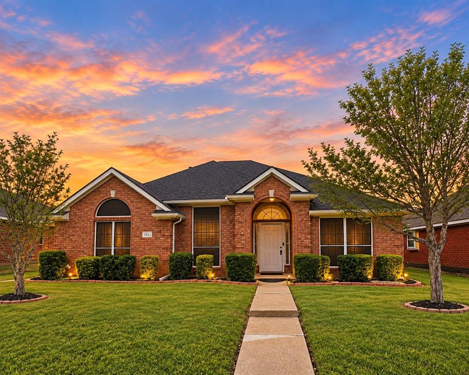 Brick exterior featuring an arched entryway, arched window accents, dark shingle roof, and a concrete walkway Brick exterior featuring an arched entryway, arched window accents, dark shingle roof, and a concrete walkway