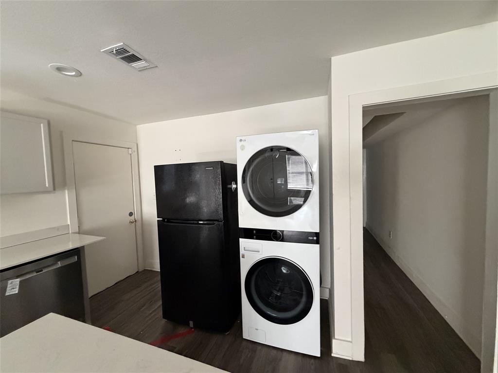 Utility in kitchen with stackable and fridge.