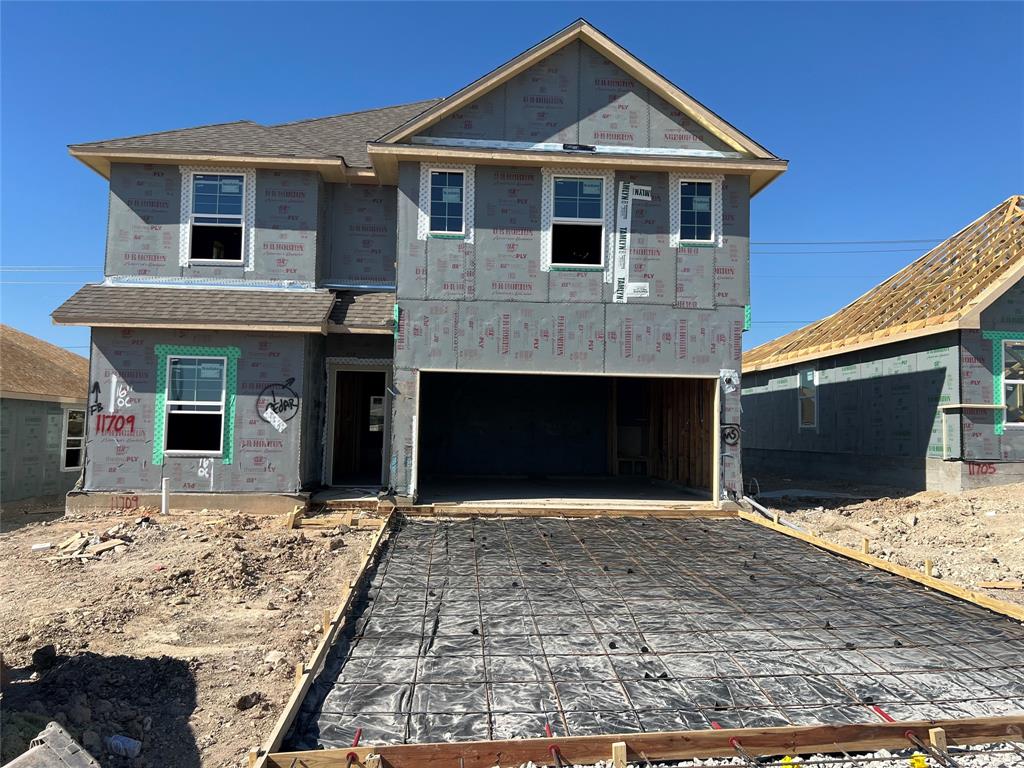 Two-story residential structure featuring a gable roof, integrated two-car garage, and installed multi-pane windows
