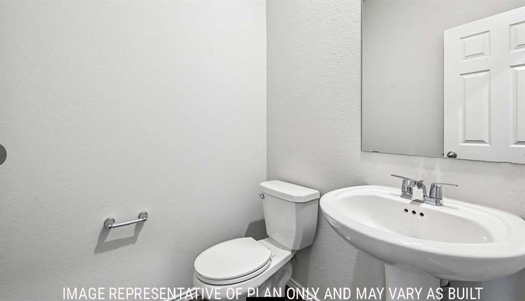 Pedestal sink featuring a chrome faucet, wall-mounted mirror, and two-piece toilet