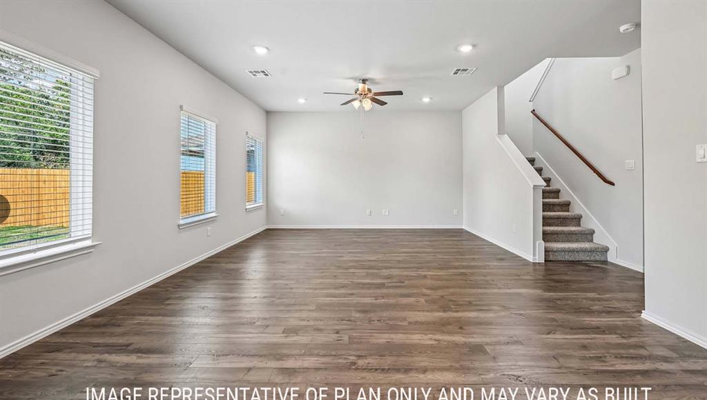 Interior space featuring wood-finish flooring, recessed lighting, a ceiling fan, windows with horizontal blinds, and a staircase with a wooden handrail