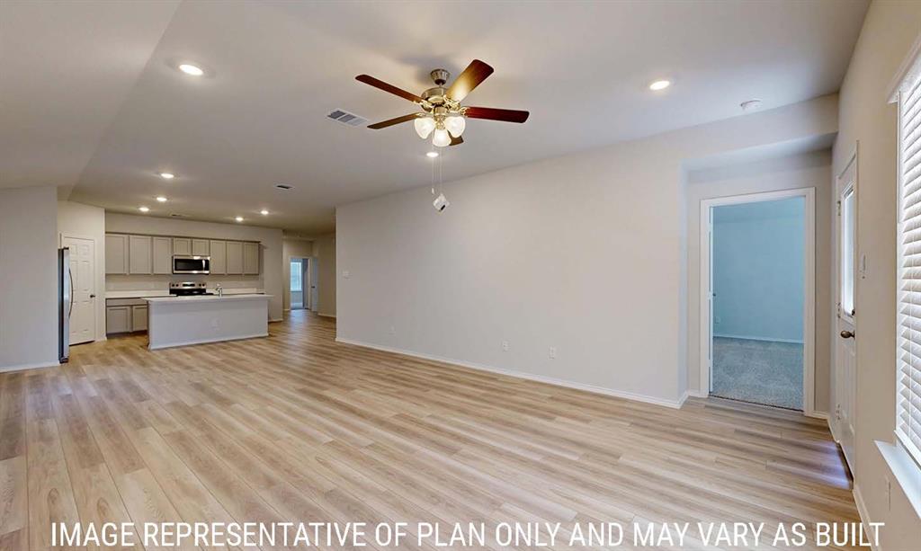 Open-concept interior featuring wood-finish flooring, recessed lighting, a ceiling fan with integrated lighting, and kitchen cabinetry with stainless steel appliances