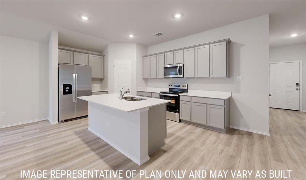 Kitchen featuring grey cabinetry, stainless steel appliances, central island with dual-basin sink, light-toned countertops, and wood-finish flooring Kitchen featuring grey cabinetry, stainless steel appliances, central island with dual-basin sink, light-toned countertops, and wood-finish flooring