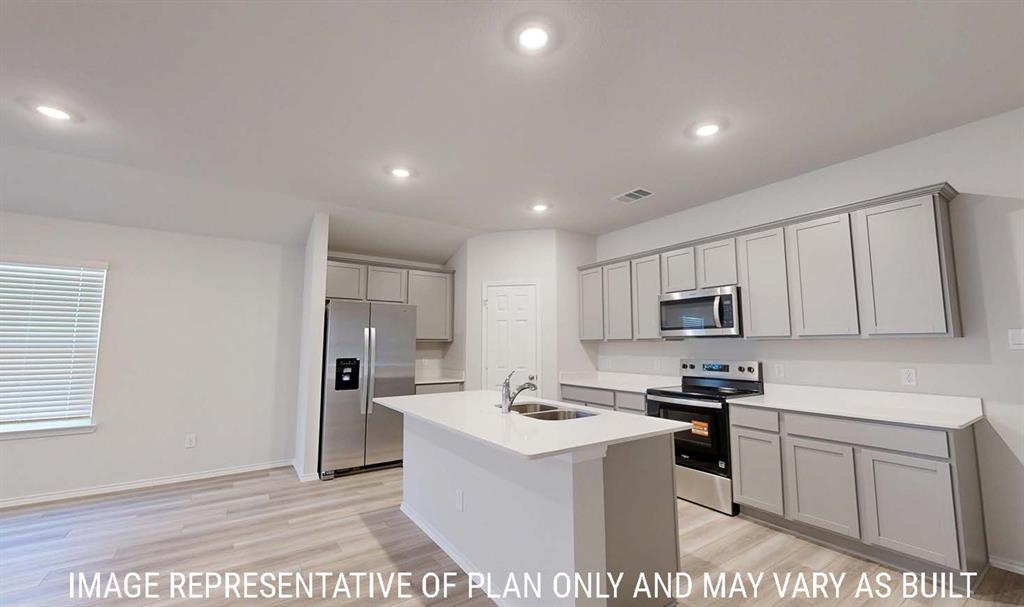 Kitchen featuring grey shaker-style cabinetry, white countertops, stainless steel appliances, a central island with a dual-basin sink, and wood-finish flooring Kitchen featuring grey shaker-style cabinetry, white countertops, stainless steel appliances, a central island with a dual-basin sink, and wood-finish flooring