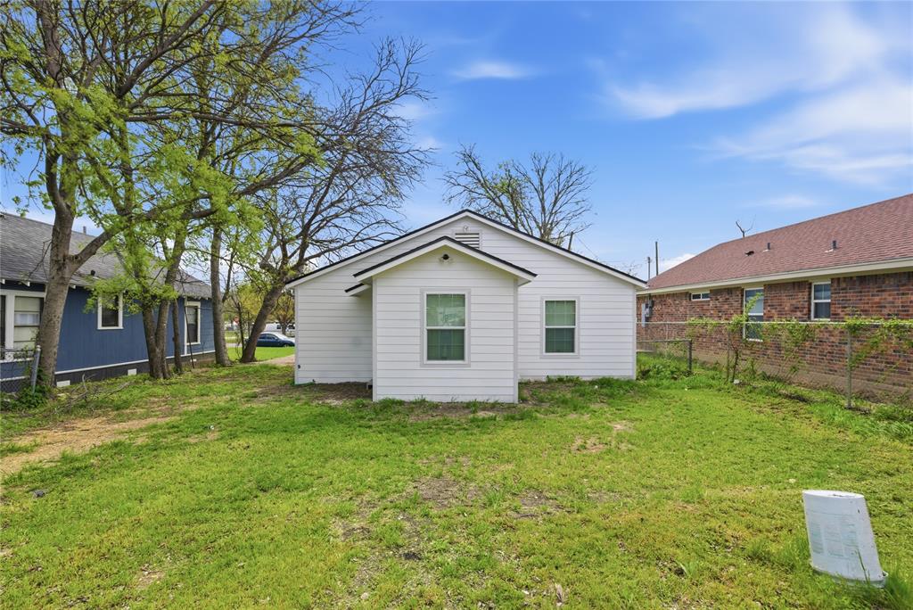 White horizontal siding exterior with a pitched roofline, large grass yard, and mature trees