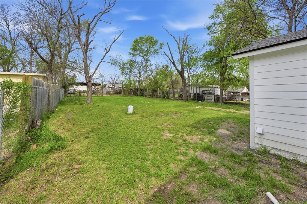 Expansive lawn featuring mature trees, chain-link fencing, and horizontal siding exterior