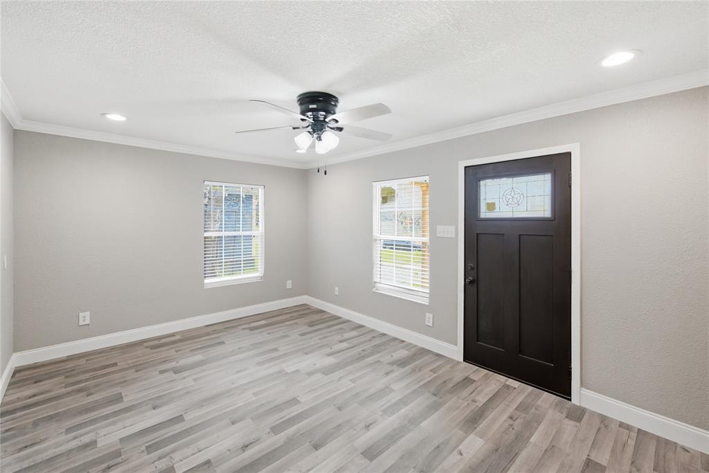 Interior space featuring wood-finish flooring, neutral wall paint, recessed lighting, a ceiling fan with integrated light fixture, and an exterior door with a decorative glass insert Interior space featuring wood-finish flooring, neutral wall paint, recessed lighting, a ceiling fan with integrated light fixture, and an exterior door with a decorative glass insert