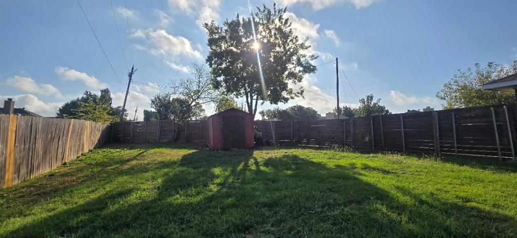 Backyard featuring a grass lawn, perimeter wood fencing, and a detached storage structure