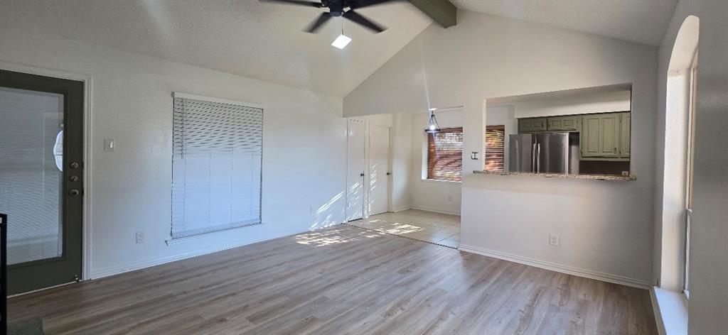 Vaulted ceilings, wood-finish flooring, ceiling fan, pass-through opening to the kitchen, and stainless steel kitchen appliances