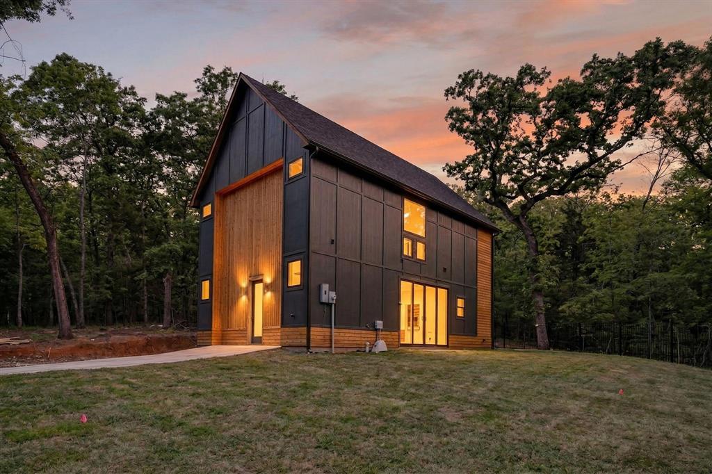 Modern two-story architectural exterior featuring dark panel siding, natural wood-finish vertical accents, a steeply pitched roof, and large glass entry doors