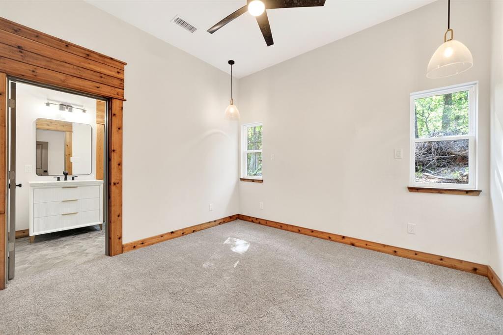 Interior space featuring wood trim accents, neutral wall-to-wall carpeting, dual hanging pendant light fixtures, and a matte black ceiling fan