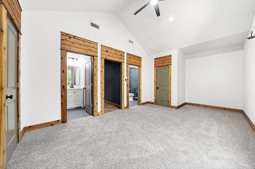Vaulted ceiling with a central paddle fan, custom wood door casing and header detail, neutral wall-to-wall carpeting, and solid-core interior doors