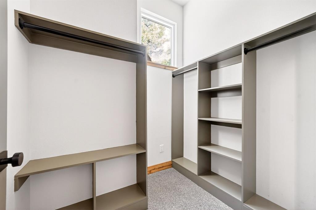 Custom storage system featuring neutral-toned cabinetry, built-in shelving, integrated garment rods, and a window allowing for natural light