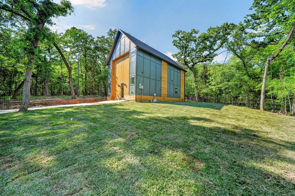 Modern architectural exterior featuring metal panel siding, vertical wood-finish siding, a steep pitched roofline, and expansive surrounding woodland Modern architectural exterior featuring metal panel siding, vertical wood-finish siding, a steep pitched roofline, and expansive surrounding woodland