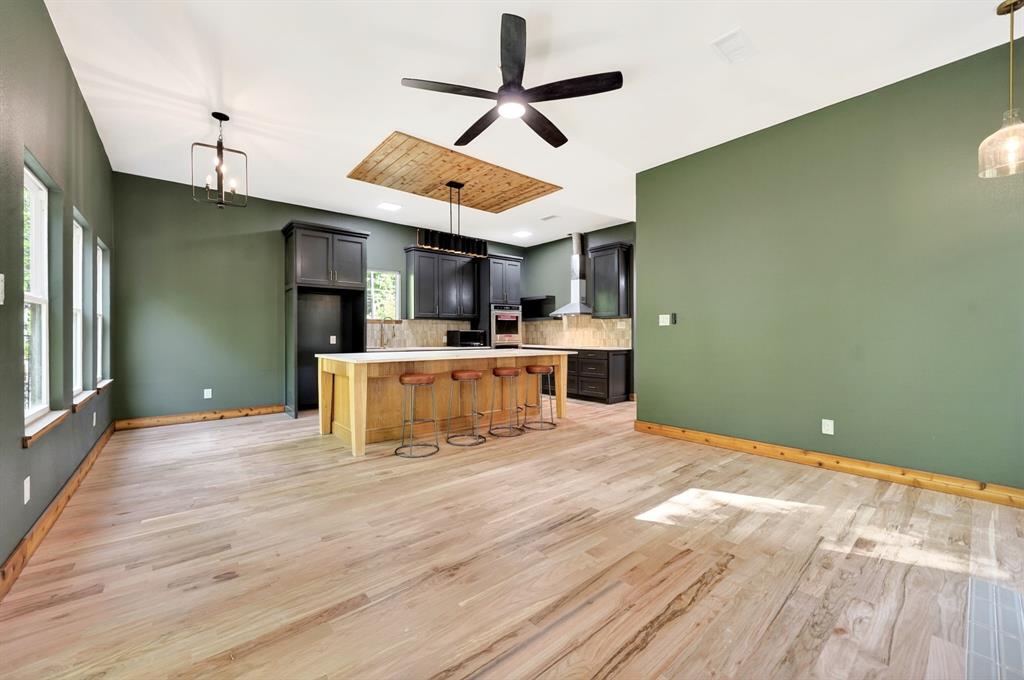 Kitchen featuring a wood-topped center island, custom dark cabinetry, wood-finish flooring, vaulted ceiling with wood paneling inlay, and integrated stainless steel appliances Kitchen featuring a wood-topped center island, custom dark cabinetry, wood-finish flooring, vaulted ceiling with wood paneling inlay, and integrated stainless steel appliances