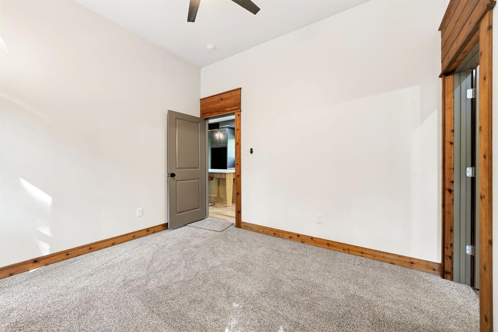 Neutral-toned carpeting, natural wood-trimmed doorways, solid-core interior door, and ceiling fan