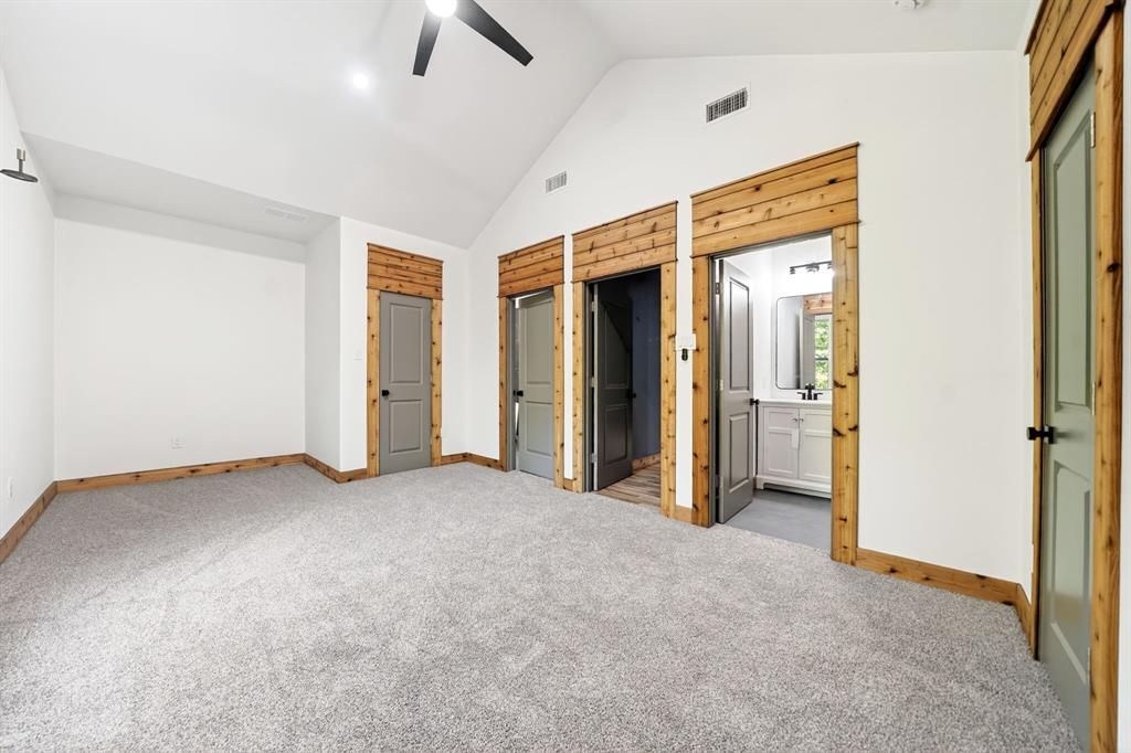 Vaulted ceilings, neutral carpeting, natural wood-finish trim, paneled interior doors, and built-in ceiling fan