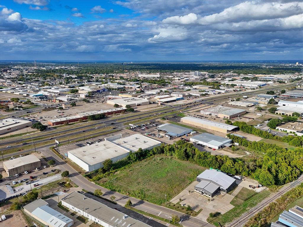 Aerial perspective of a commercial lot with paved access, concrete parking area, and multi-use warehouse facility