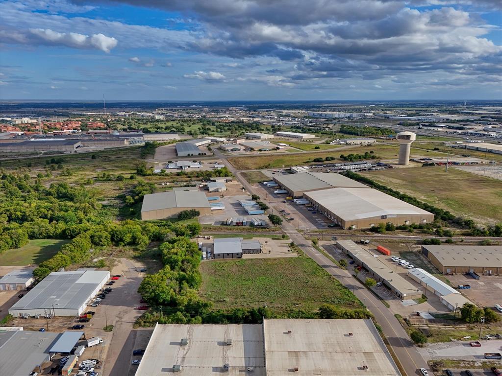Aerial perspective of industrial site featuring extensive acreage, multiple metal-clad structures, dedicated paved parking areas, and established regional road access