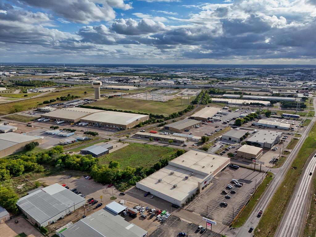 Aerial perspective of industrial complex featuring expansive paved parking lots, multi-bay warehouse structures, metal roof systems, and proximity to regional transportation infrastructure