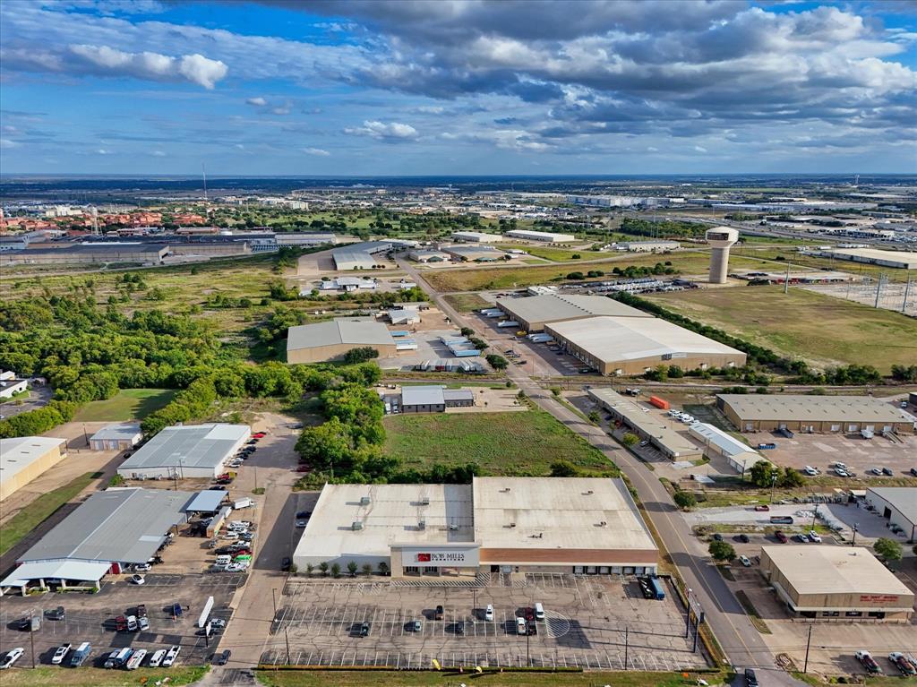 Industrial facility featuring an expansive paved parking area, multiple loading docks, and a flat-roofed commercial structure situated within an industrial corridor