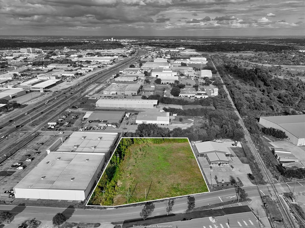 Aerial perspective of cleared, rectangular parcel featuring road frontage, bordering vegetation, and proximity to regional transportation infrastructure