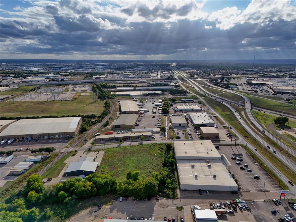 Aerial view of a commercial site featuring multiple industrial structures, paved parking areas, and frontage along a major highway