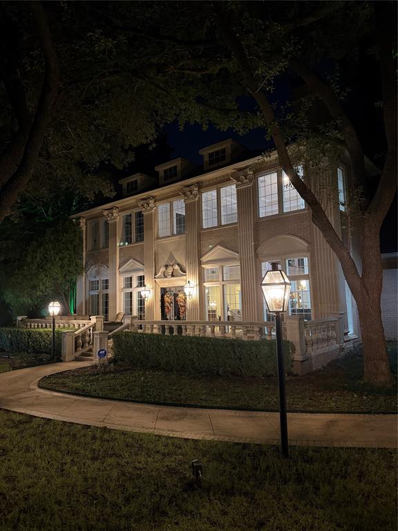 Multi-story exterior featuring classical pilasters, decorative molding, stone-finish balustrades, multi-pane windows, and a paved walkway
