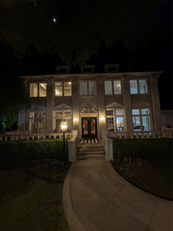Two-story symmetrical exterior featuring classical columns, arched window detailing, stone balustrade, and a decorative entryway pediment