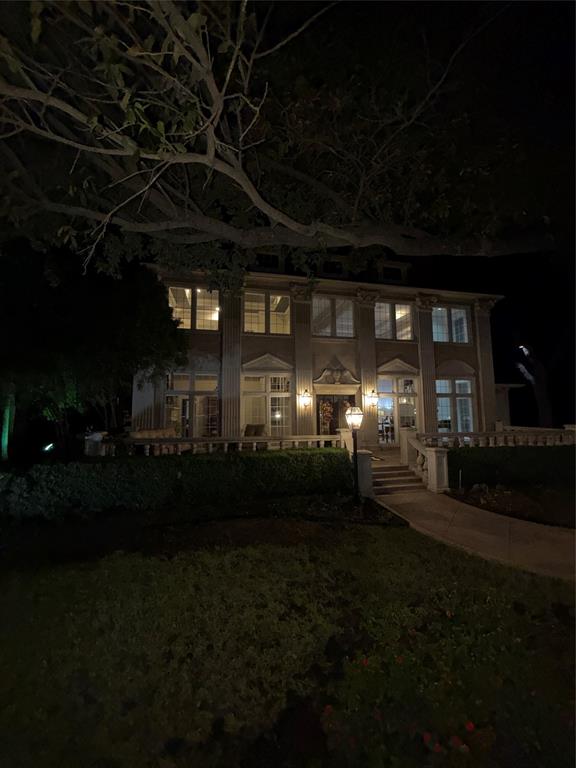 Two-story residence featuring a columned facade, stone balustrade terrace, multipane windows, and an arched entryway