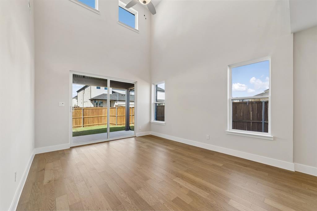 Double-height ceiling featuring recessed lighting and a ceiling fan, wood-finish flooring, and sliding glass doors with access to the rear exterior