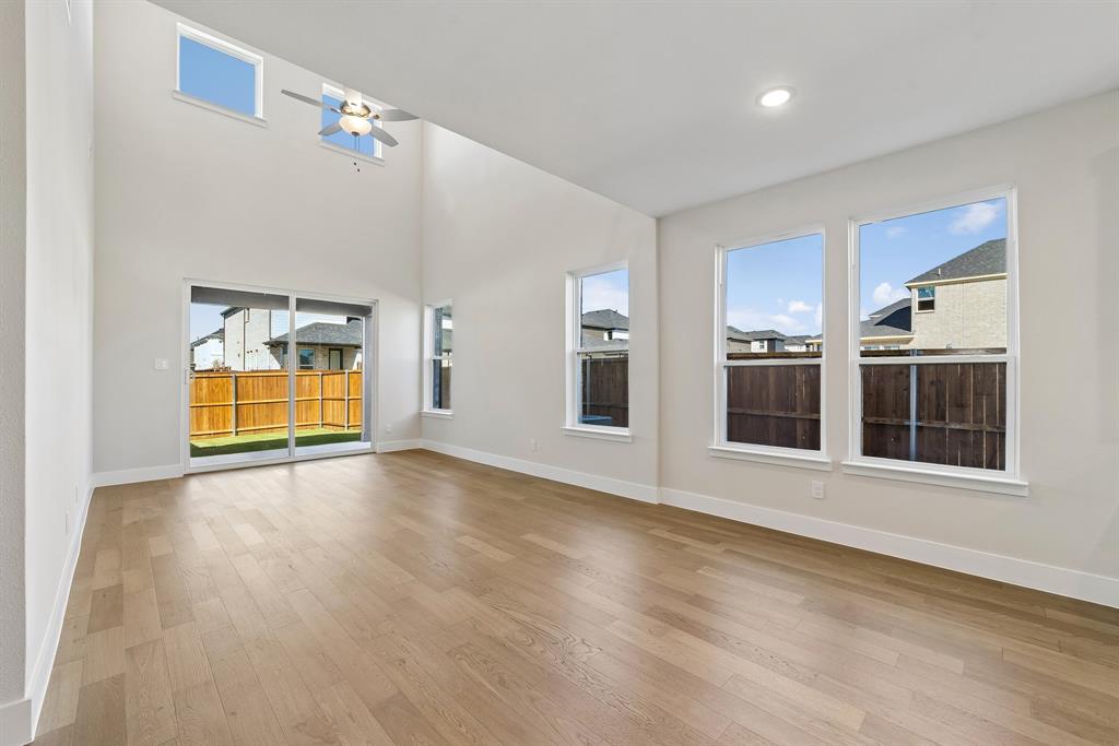 High-ceiling interior featuring wood-finish flooring, recessed lighting, a ceiling fan, and large windows with integrated sliding glass doors