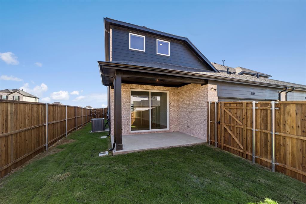Rear exterior featuring a covered concrete patio, brick and horizontal siding facade, sliding glass door, and full wood privacy fencing