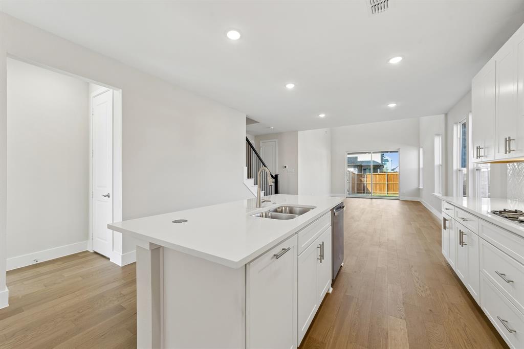 Kitchen featuring white cabinetry, quartz countertops, wood-finish flooring, recessed lighting, and a stainless steel dual-basin sink