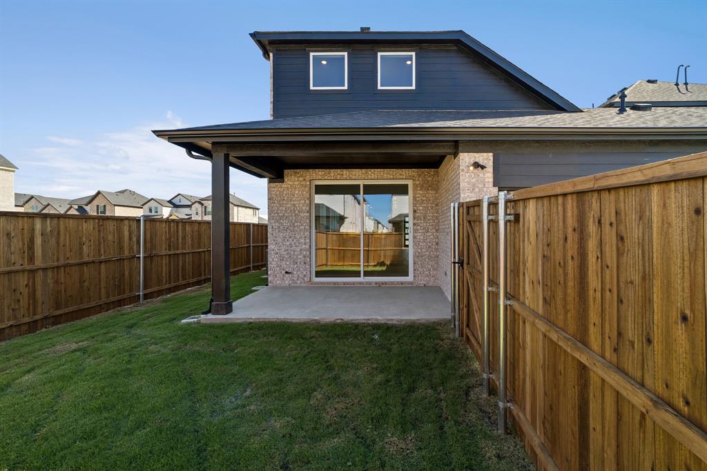 Rear exterior featuring a covered patio, brick masonry, horizontal lap siding, and a full-height wood privacy fence