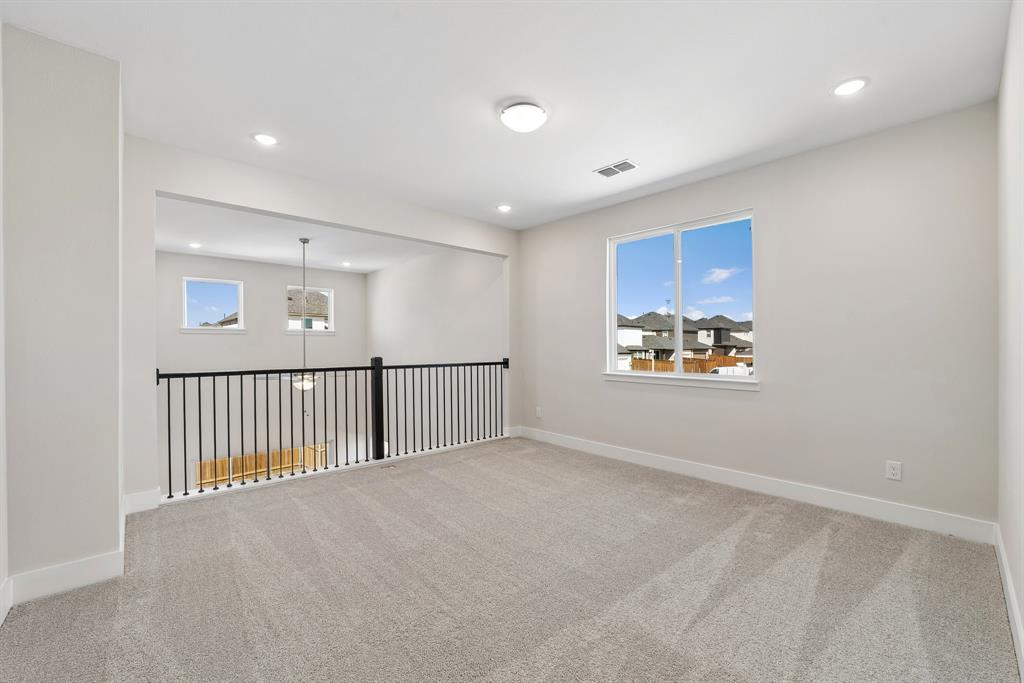 Neutral-toned interior featuring wall-to-wall carpeting, recessed lighting, matte black metal spindle railing, and expansive windows
