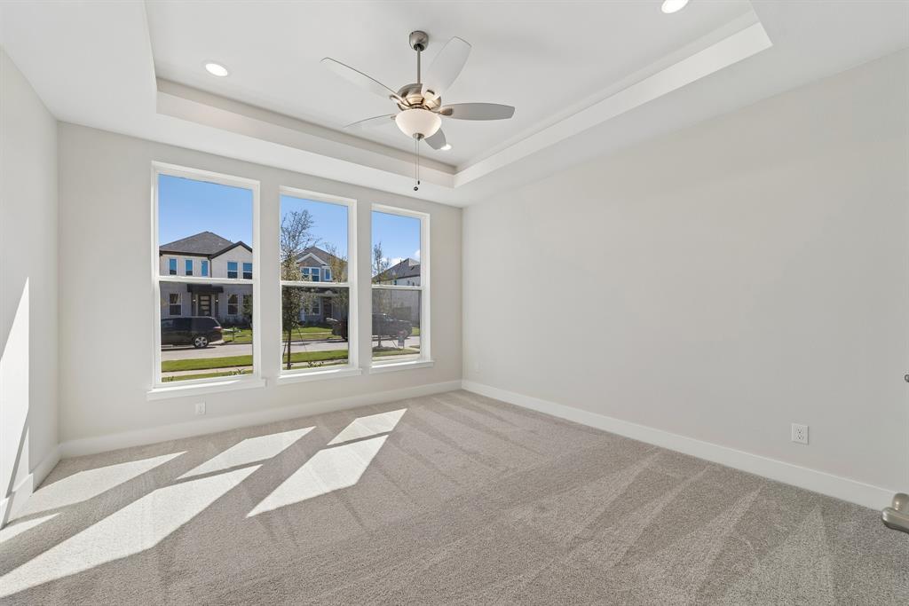 Tray ceiling with recessed lighting, integrated ceiling fan, and triple pane window configuration featuring neutral carpeting