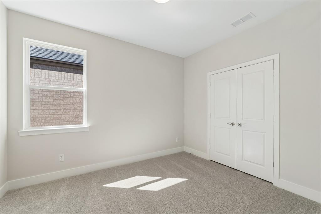 Neutral-toned room featuring plush wall-to-wall carpeting, dual-panel interior closet doors, and a single-pane window with brick exterior detail