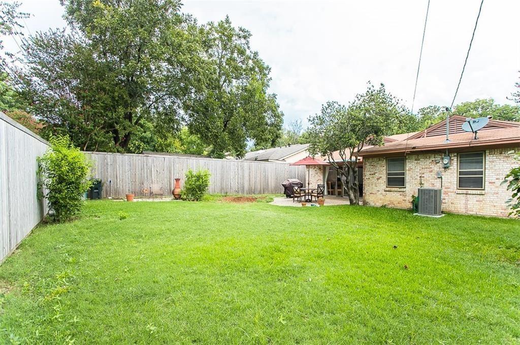 Backyard featuring a privacy fence, concrete patio, masonry exterior, and mature landscaping
